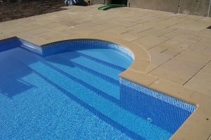 Swimming pool copings in Timsbury Sandstone with Roman End and matching paving.
